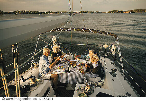 Heterosexual couples toasting wineglasses while spending leisure time in sailboat