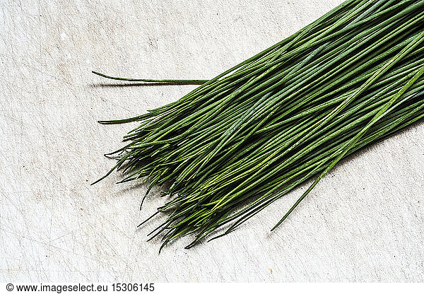 High angle close up of a bunch of fresh chives on white background.