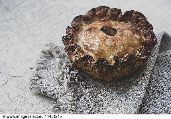 High angle close up of a freshly baked raised Pork Pie on a grey fabric napkin.