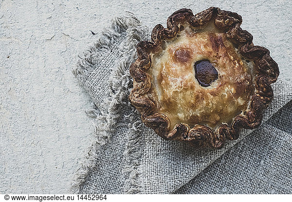 High angle close up of a freshly baked raised Pork Pie on a grey fabric napkin.