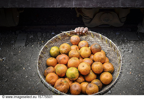 High angle close up of basket of orange citrus fruits in Myanmar.