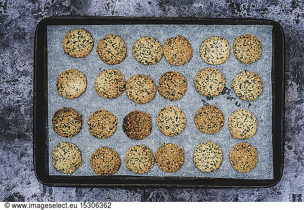 High angle close up of freshly baked seeded crackers on a baking tray.