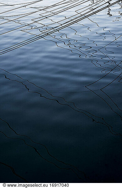 High angle close up of mooring lines and their shadows on the water surface.