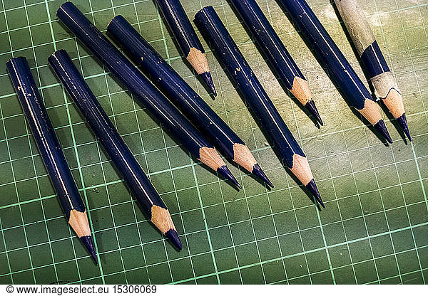 High angle close up of sharpened blue pencils on green cutting mat.