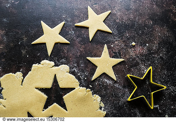 High angle close up of star-shaped cookies cut out of cookie dough.