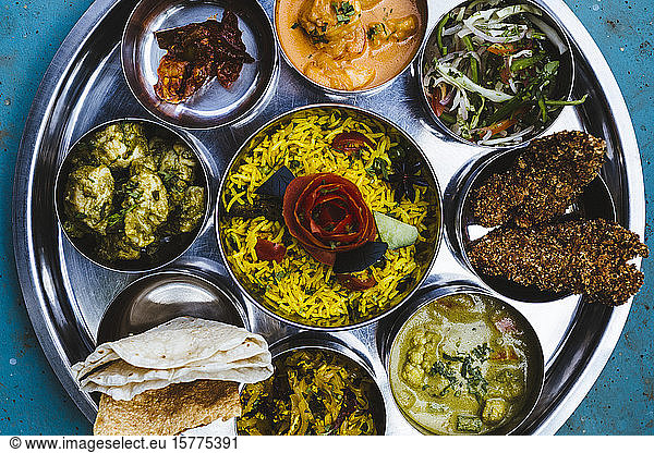 High angle close up of traditional Indian lunch with rice  various curries  pickles  and vegetables.