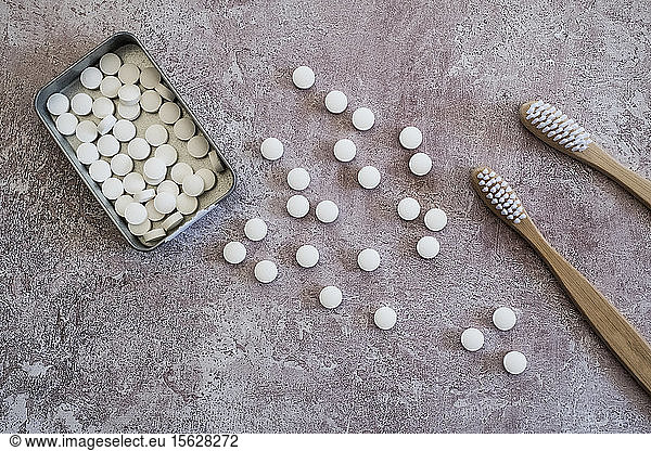 High angle close up of two wooden toothbrushes and pills in metal box.