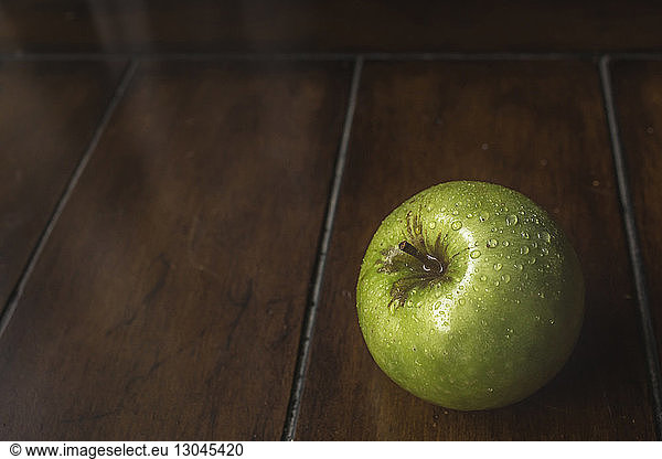 High angle close-up of wet Granny Smith apple on wooden table