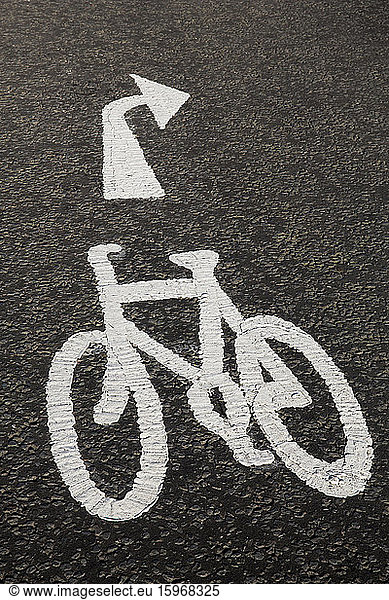 High angle close up of white bicycle lane sign on concrete path.