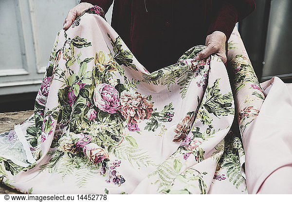 High angle close up of woman holding pink fabric with floral pattern.