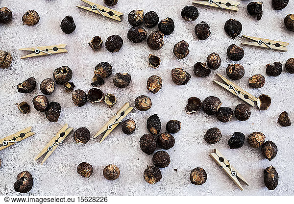 High angle close up of wooden clothes pegs and dried brown soap nuts.