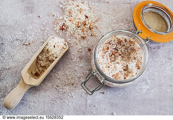 High angle close up of wooden spoon and glass jar with coarse salt.