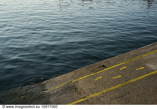 High angle close up of yellow footprints and lines painted on asphalt ground in a harbour.