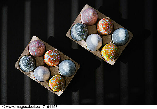 High angle of colorful Easter eggs in egg carton on black background