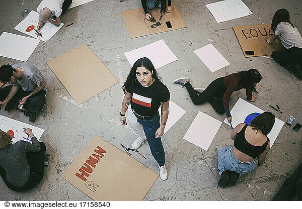 High angle portrait of woman standing while male and female activist preparing signboards in building