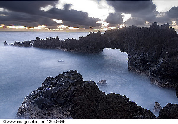 High angle scenic view of volcanic rocks in sea against stormy clouds at Waianapanapa State Park