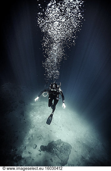 High angle underwater view of diver wearing wet suit and flippers  air bubbles rising.