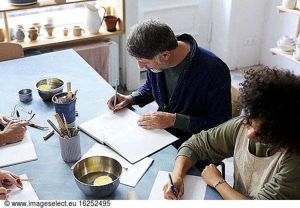 High angle view man and woman drawing at table during art class