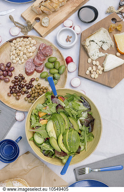 High angle view of a cheese board  cheese  olives  nuts and a bowl of salad on a table.