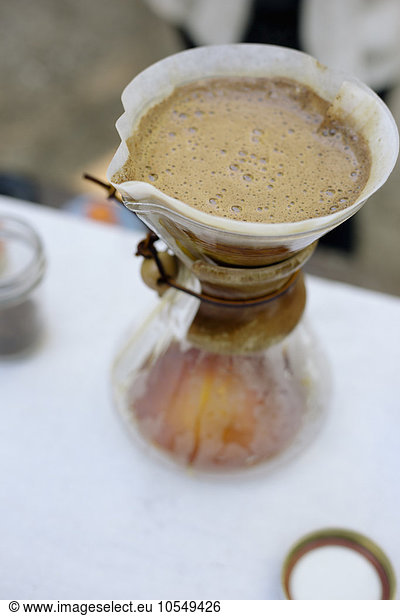 High angle view of a glass coffee maker and filter paper with coffee and water filtering through