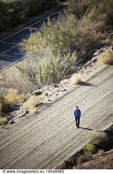High angle view of a lone woman standing in the middle of a dirt road. Utah.