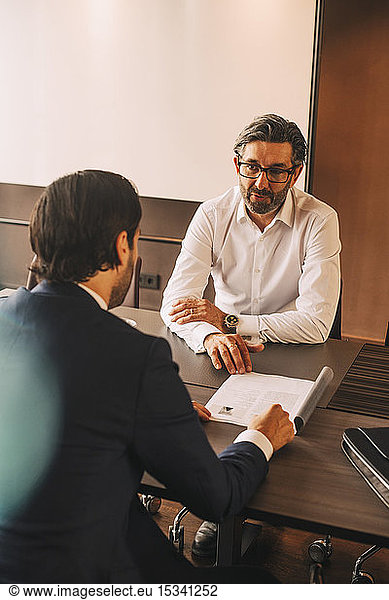 High angle view of advisor explaining document to businessman in meeting at law office