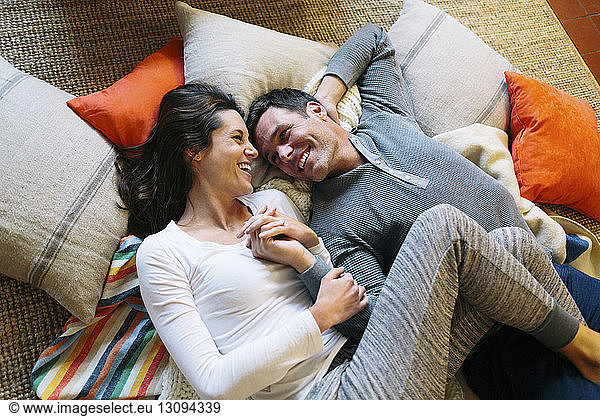 High angle view of affectionate couple lying on carpet at home
