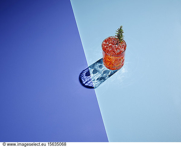 High angle view of alcohol with ice cubes on colored background