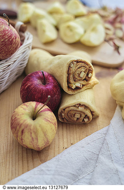 High angle view of apple slices and ground cinnamon rolled in pastry dough on kitchen counter