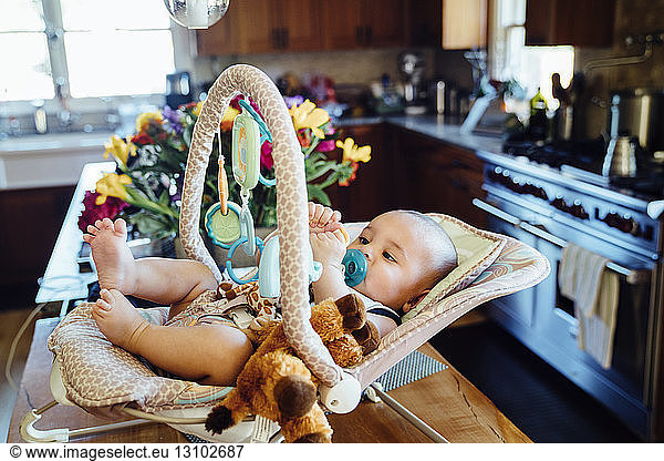 High angle view of baby boy in baby seat in kitchen at home