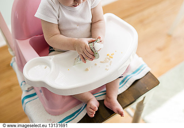 High angle view of baby girl sitting on high chair