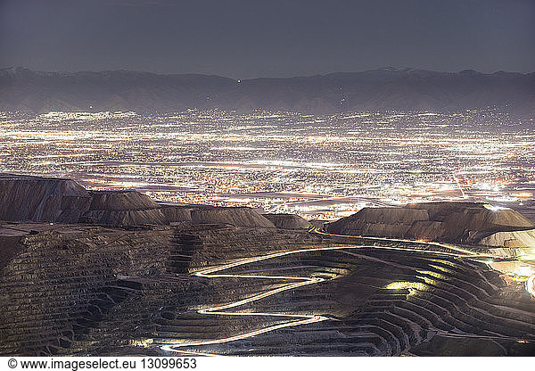 High angle view of Bingham Canyon against illuminated cityscape