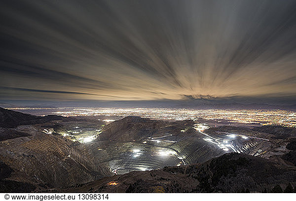 High angle view of Bingham Canyon and illuminated cityscape against cloudy sky