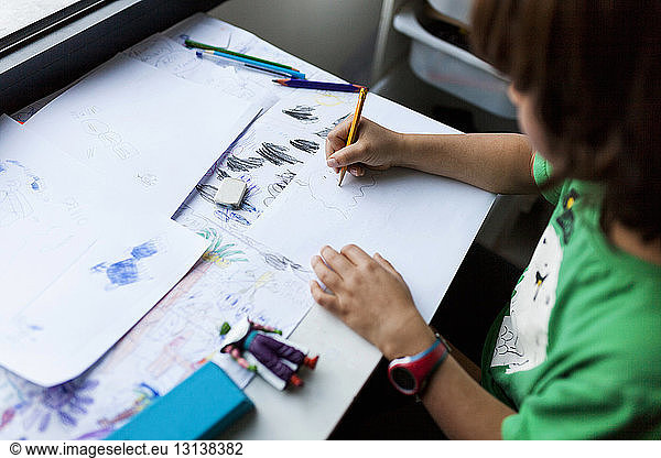 High angle view of boy drawing on paper at table