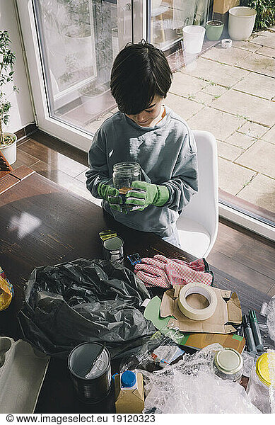High angle view of boy holding glass container at home