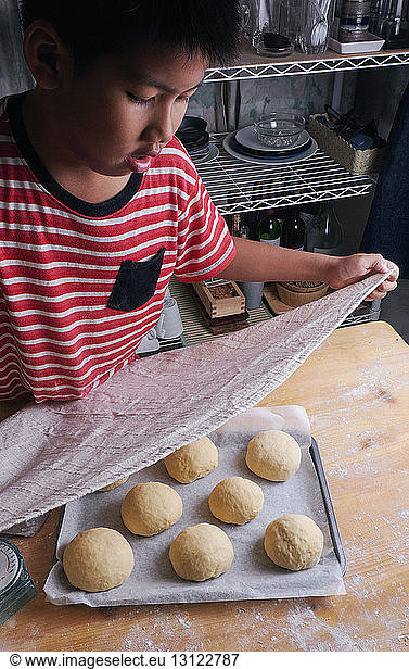 High angle view of boy making buns on kitchen counter at home