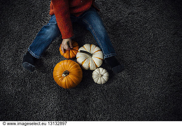 High angle view of boy playing with pumpkins at home during Halloween
