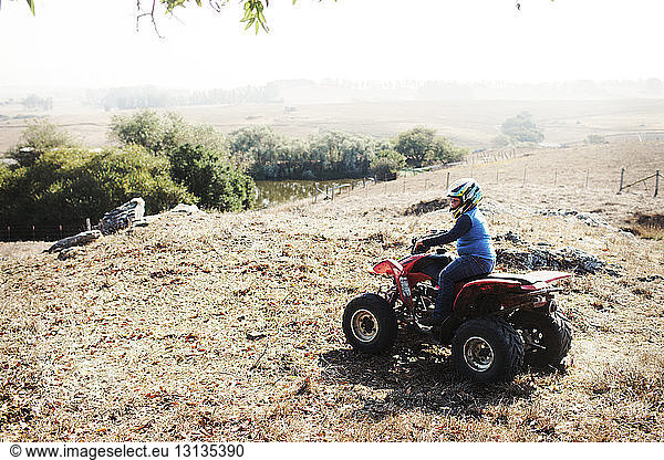 High angle view of boy riding quadbike on field during sunny day