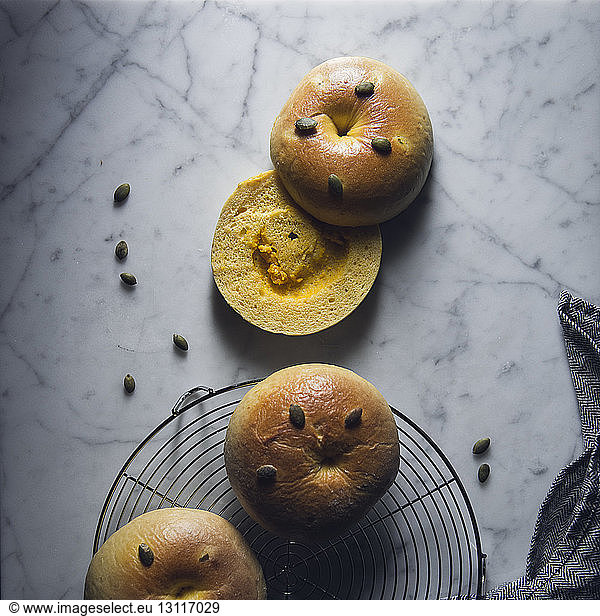 High angle view of buns with sunflower seeds and colander on marble