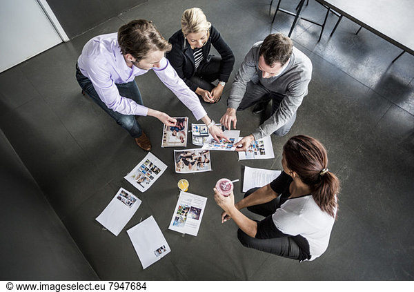 High angle view of business colleagues working with photographs in office
