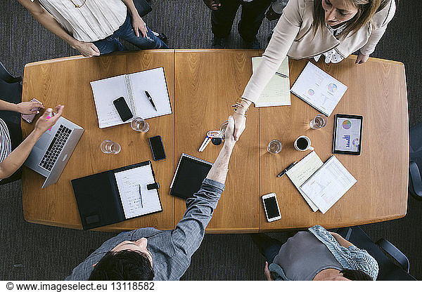 High angle view of business people shaking hands in board room