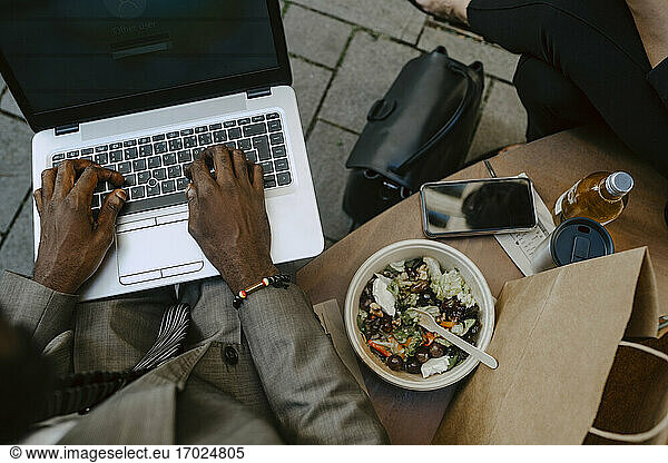 High angle view of businessman's hands working on laptop