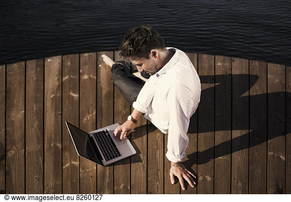 High angle view of businessman using laptop on boardwalk