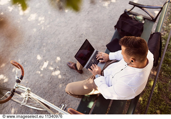 High angle view of businessman using laptop while sitting on park bench