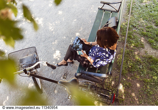 High angle view of businesswoman using digital tablet on park bench