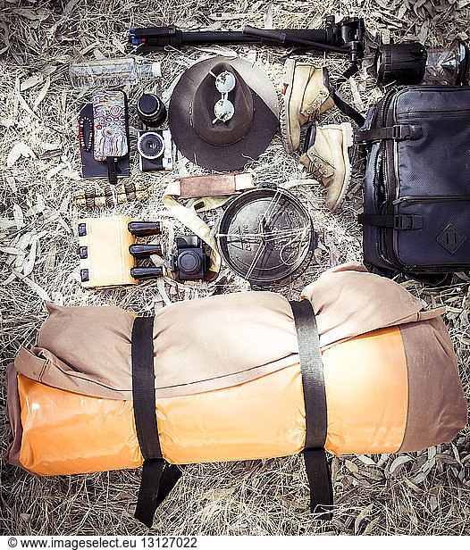 High angle view of camping equipment with personal accessories on field