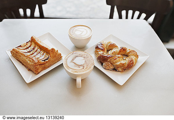High angle view of cappuccino and pastries on table in cafe