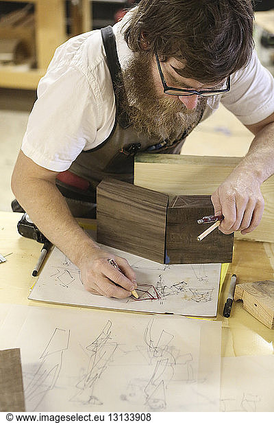 High angle view of carpenter drawing sketch while standing at workbench
