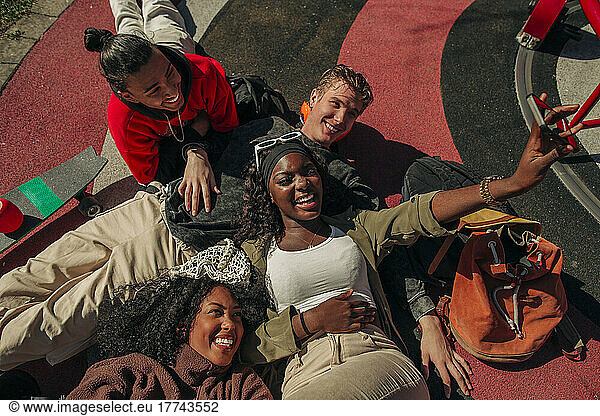 High angle view of cheerful multiracial friends taking selfie through smart phone in playground