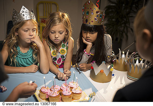 High angle view of children looking at cup cakes on table
